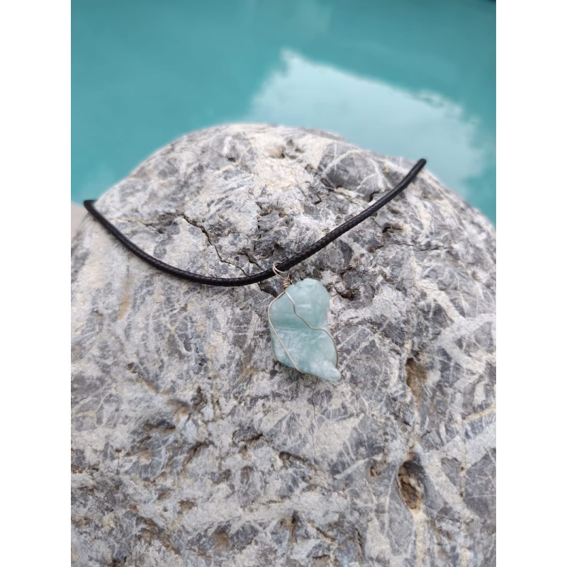 pendentif en aigue marine brute présenté sur galet, bijou artisanal et pierre naturelle